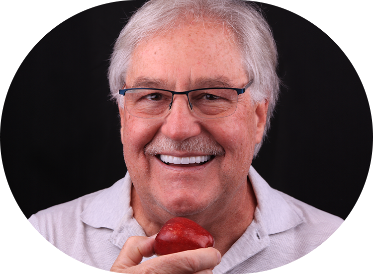 implant denture patient at odyssey dental holding an apple